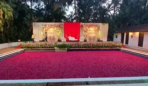 Rose petal covered pool in front of the poolside wedding reception stage at Exotica