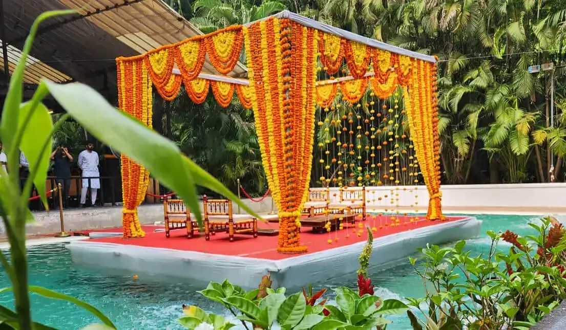 Floating mandap decorated with marigold garlands over the turquoise pool at Exotica Tropical Retreat