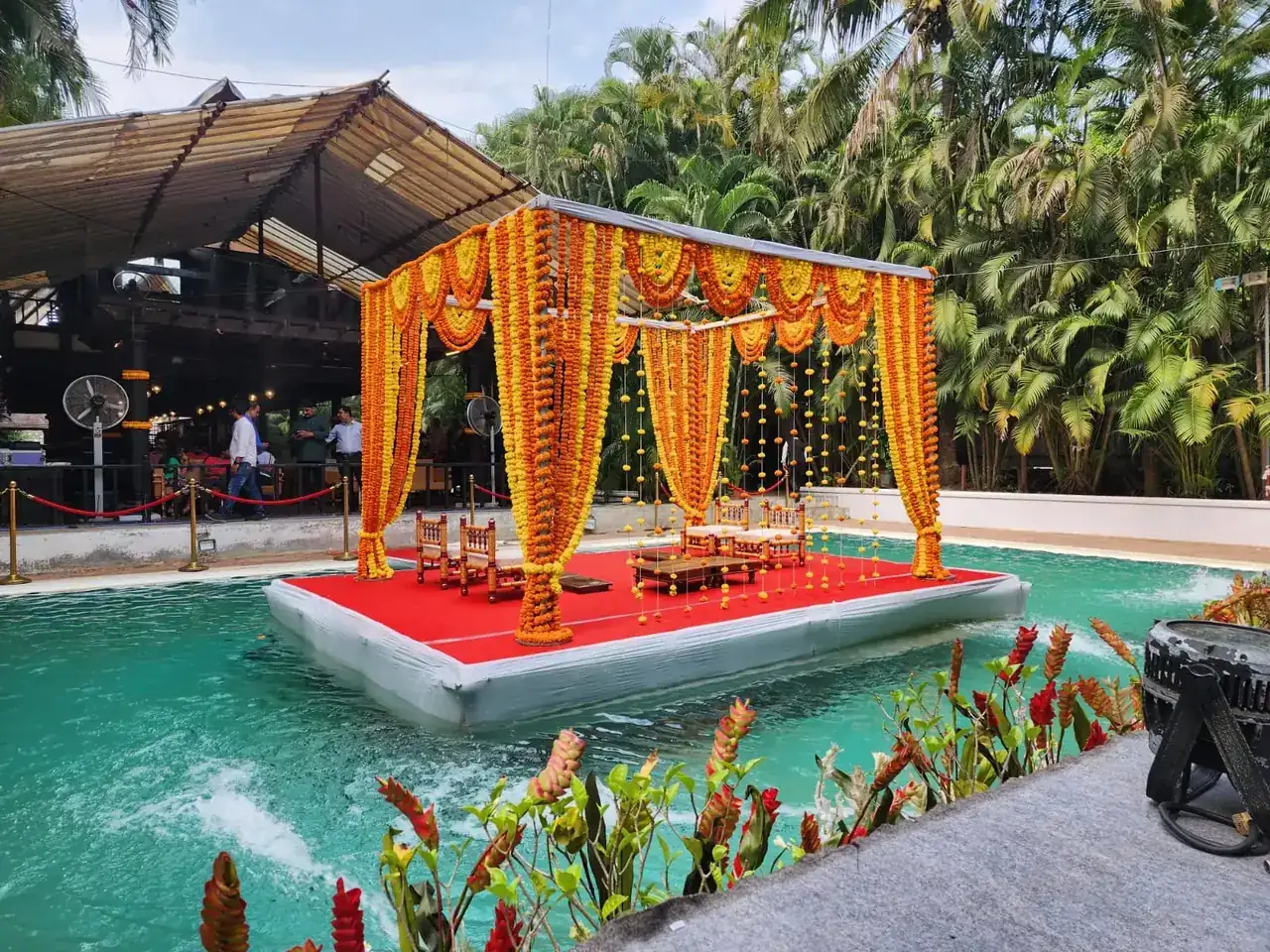 Wide view of the marigold-decorated floating mandap on the pond at Exotica