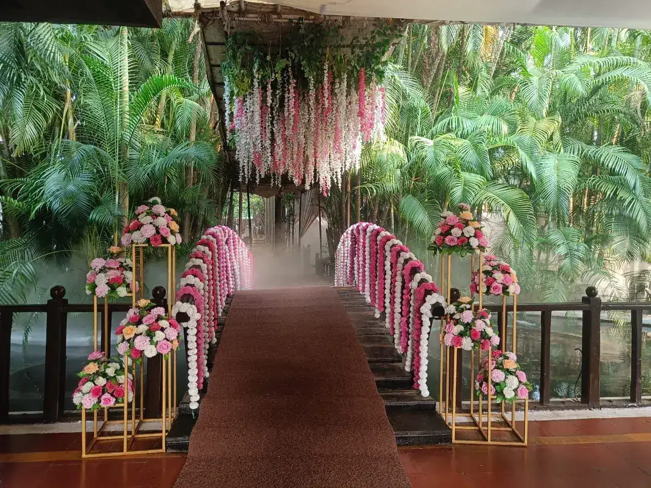 Flower-decorated bridge walkway with pink and white garlands at Exotica Tropical Retreat