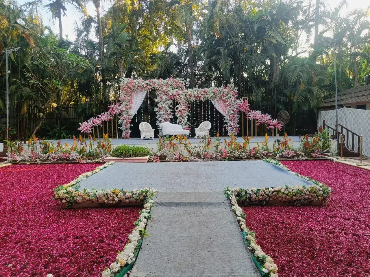 Rose petal covered lawn with a white floral wedding stage at Exotica Tropical Retreat