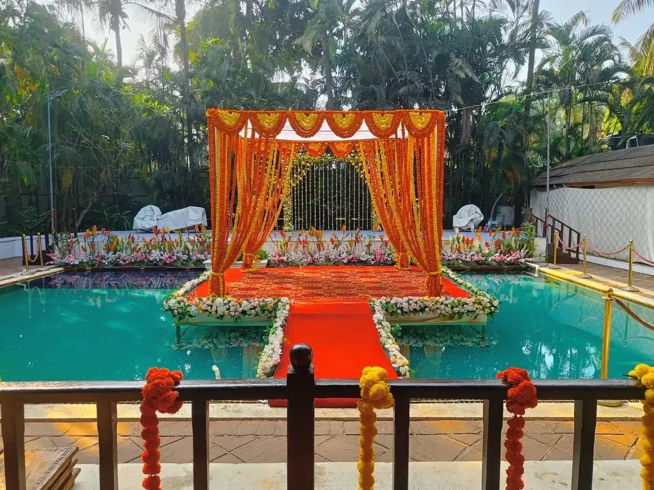 Marigold-draped floating mandap over the turquoise pool at Exotica Tropical Retreat, Yeoor Hills