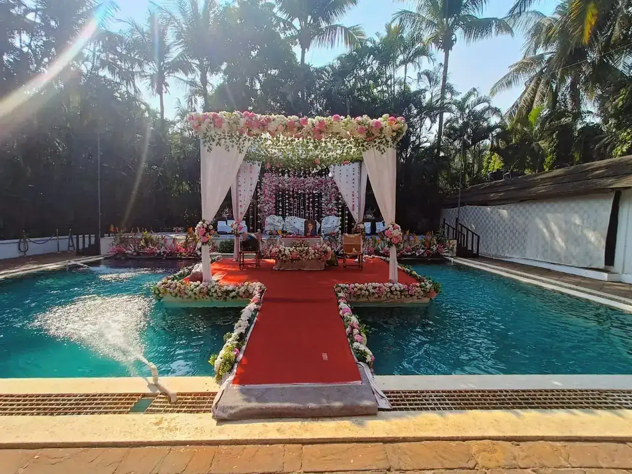 White-draped floating mandap with red carpet aisle over the pool at Exotica