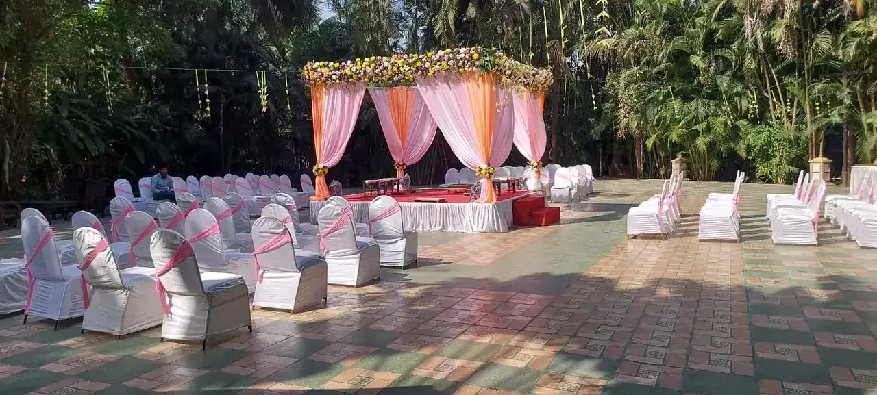 Garden wedding ceremony seating with white chair covers and floral mandap at Exotica