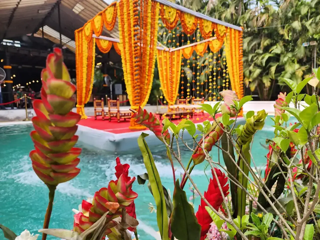 Floating mandap glimpsed through tropical flowers at Exotica