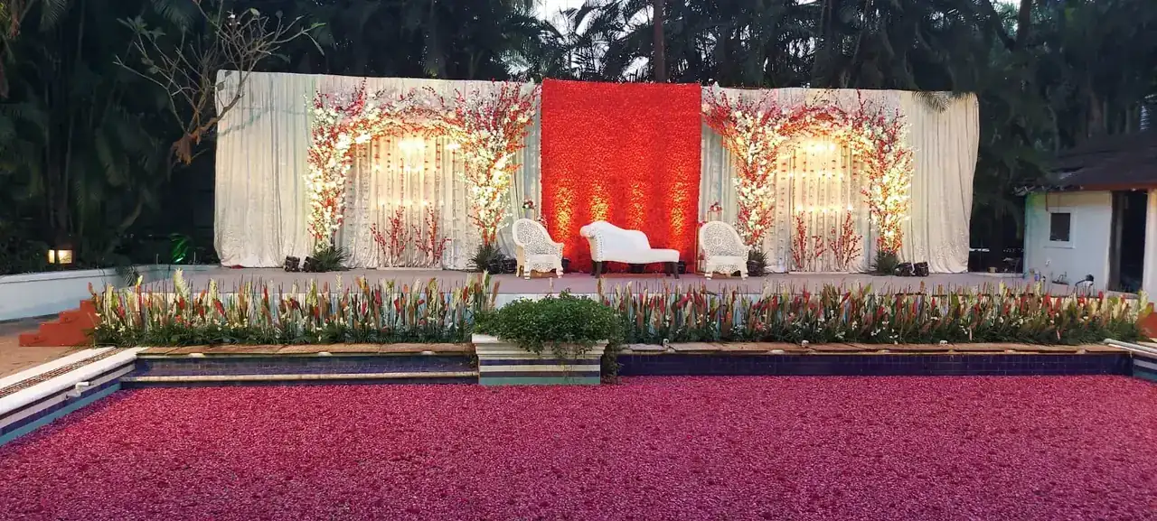Red and white reception stage behind the petal-covered pool at Exotica